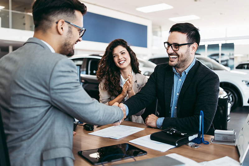 Businessmen shaking hands during a car purchase agreement.