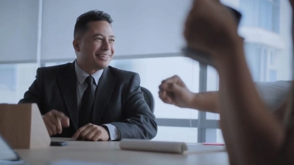 Businessman smiling during a meeting with a fist bump gesture.