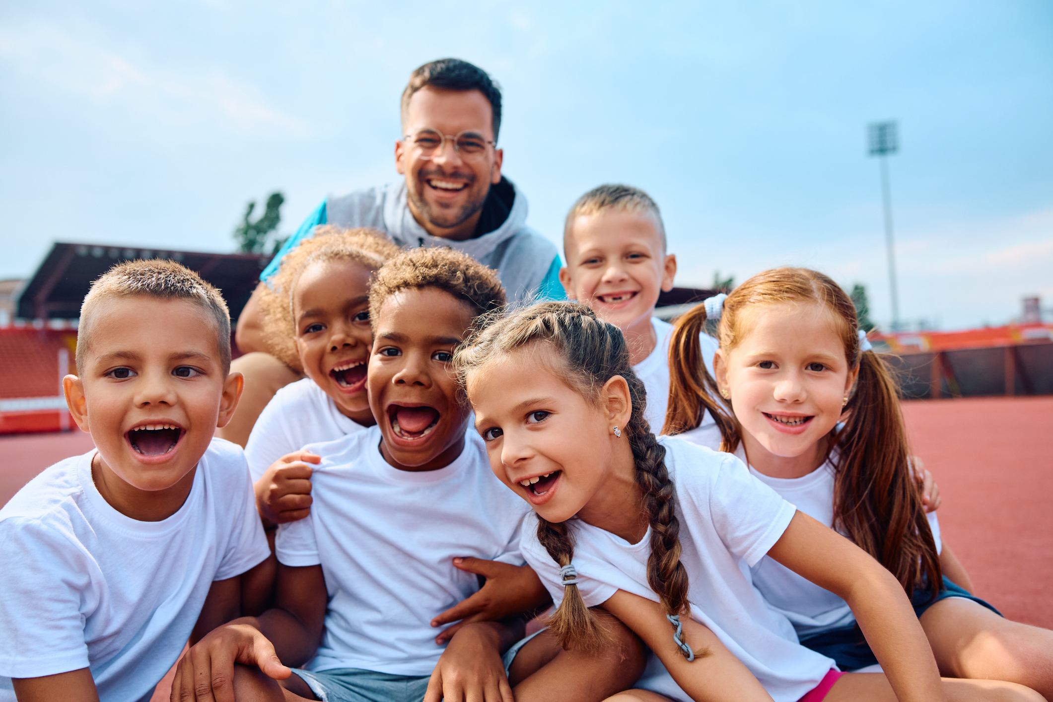 Smiling children and coach at outdoor track