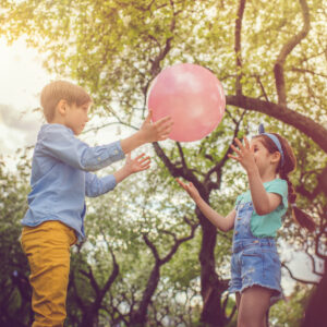 Children playing with pink balloon in park