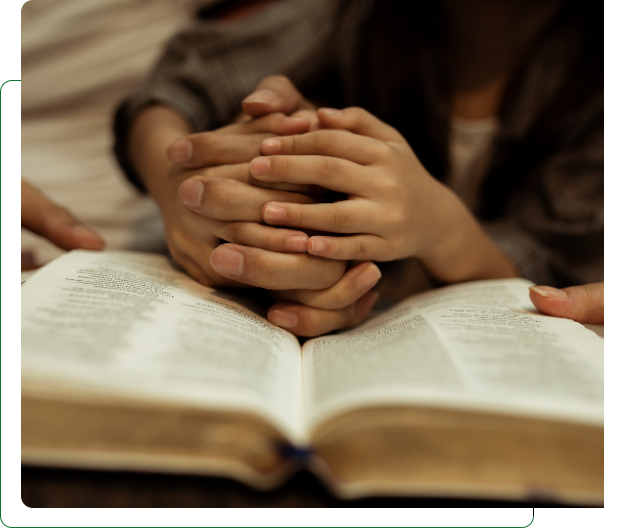 Hands clasped in prayer over open Bible