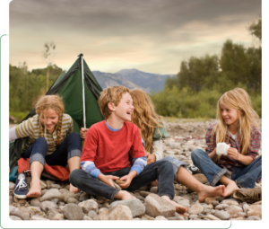 Kids laughing by tent on rocky riverbank