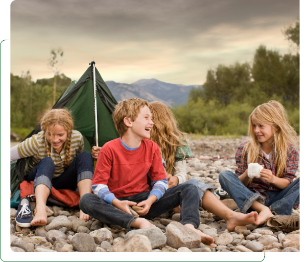 Kids laughing by tent on rocky riverbank