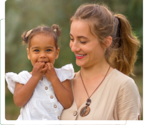 Smiling mother holding toddler daughter outdoors