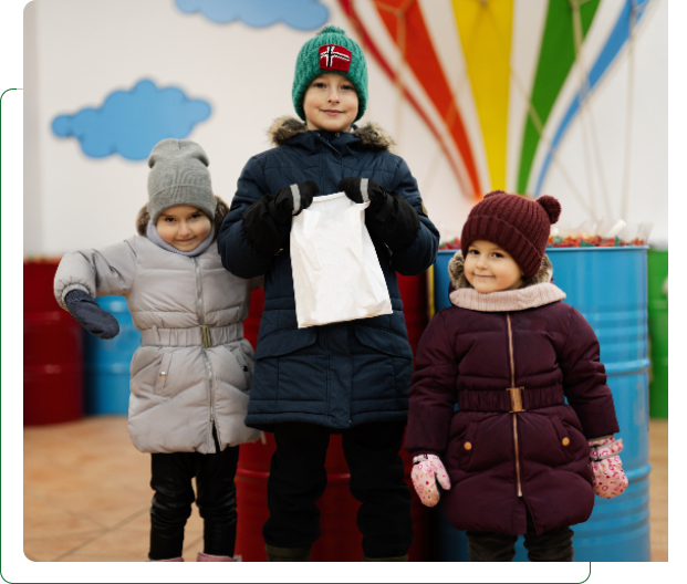 Three children in winter coats holding white bag